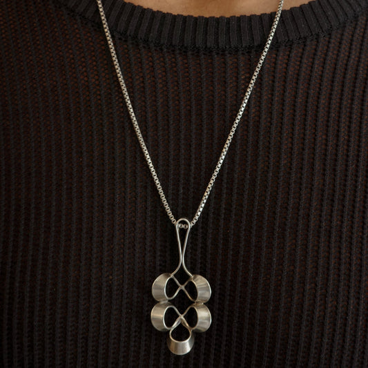 Silver necklace with a pendant worn by a person against a neutral background